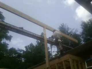 Carpenter setting a ridge beam over a new addition frame — Ice Dam Removal by Roofing Brothers in Glenshaw