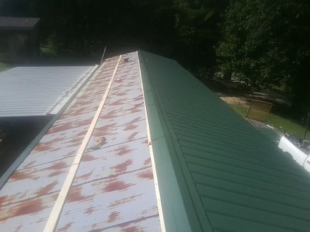 Old rusted panels beside newly installed green metal roofing — Wind Damage Roof Repair by Roofing Brothers in Glenshaw
