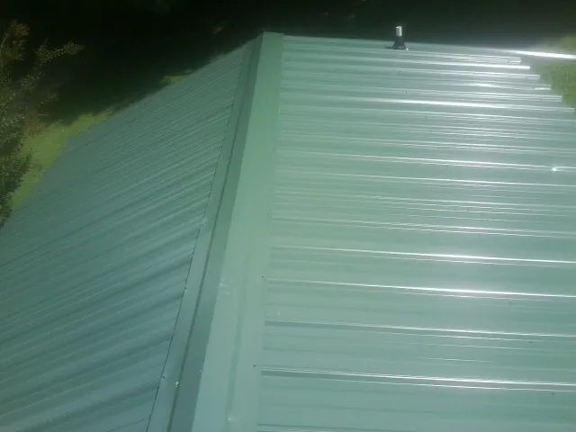 New green metal panels meeting at the ridge of a roof — Flat Roof Repair work by our crew in Glenshaw