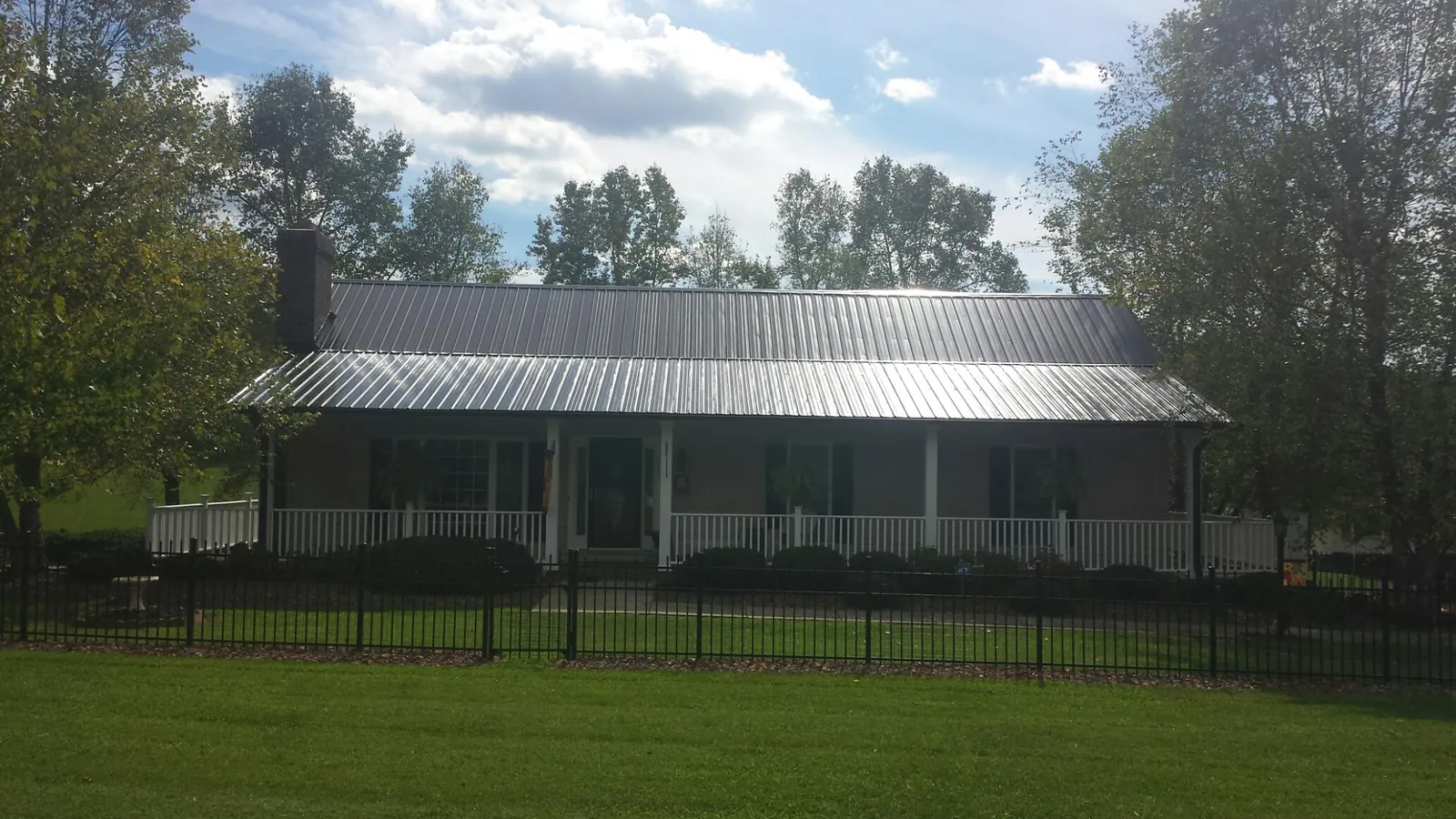 Gray metal roof on a brick ranch with a full width front porch — Gutter Guard Installation work by our crew in Glenshaw