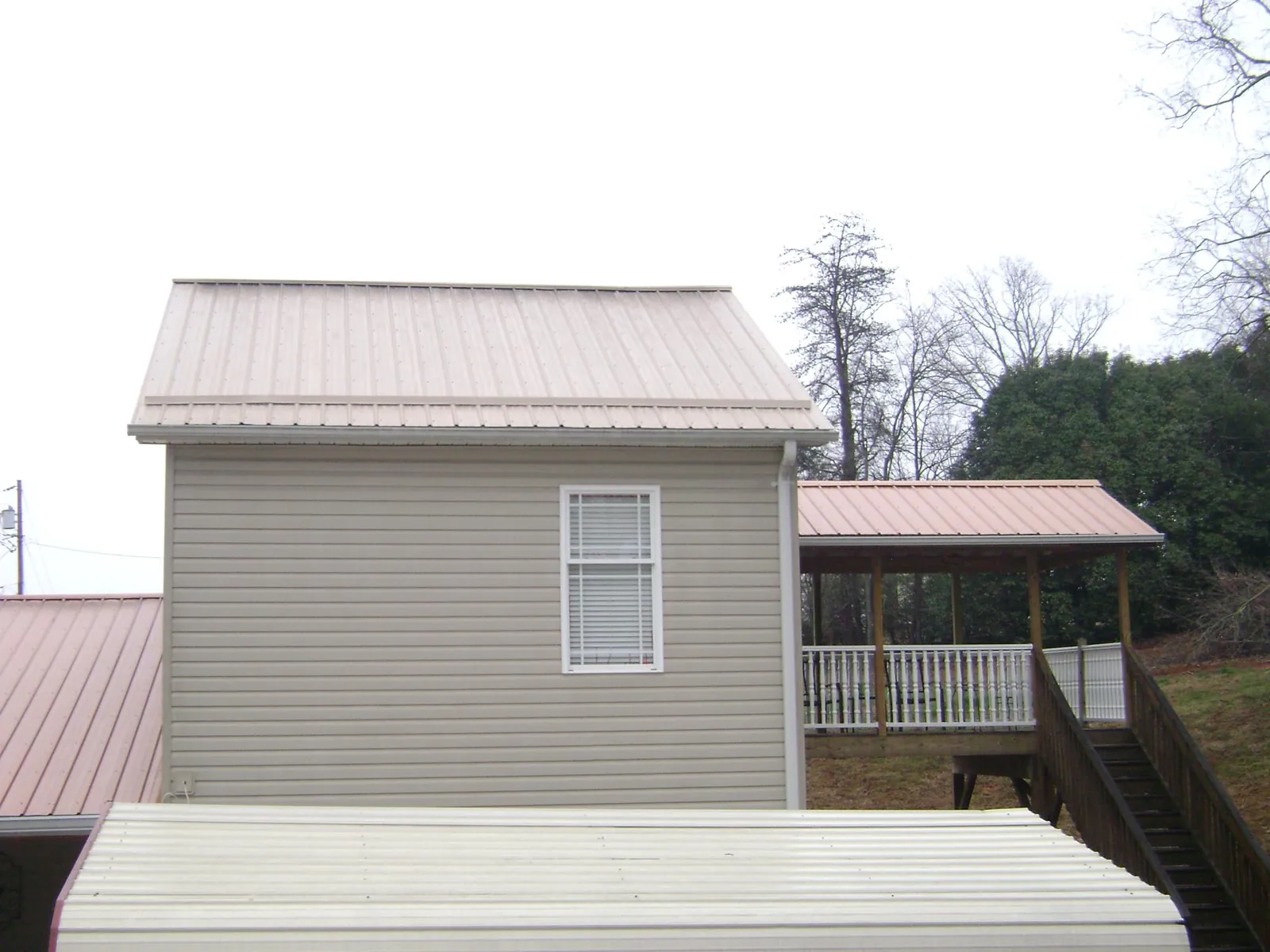 Tan metal roofs on a two story addition and attached porch, from a Roof Replacement job in Glenshaw