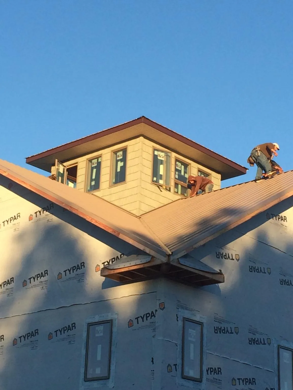 Roofers working around a rooftop cupola on a new metal roof at sunset — Roof Waterproofing in Glenshaw by Roofing Brothers